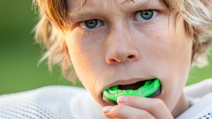 Teen boy placing athletic mouthguard