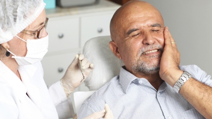 Man with hand on cheek dental visit