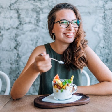Woman smiling while eating yogurt and fruit