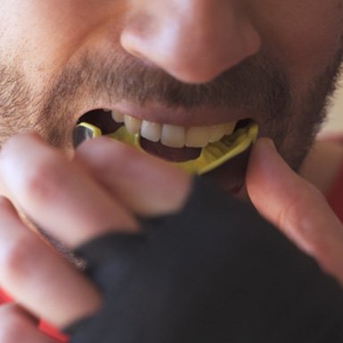 Man putting yellow and black mouthguard in place