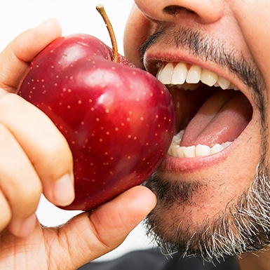 Man biting into red apple
