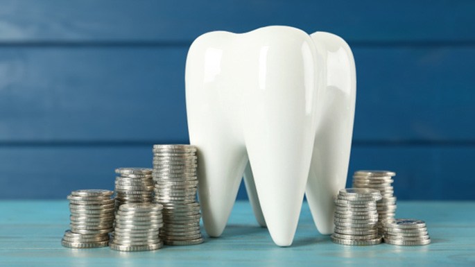 A large model tooth surrounded by silver coins