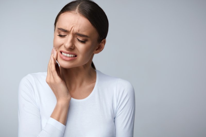 person with tooth pain holding cheek