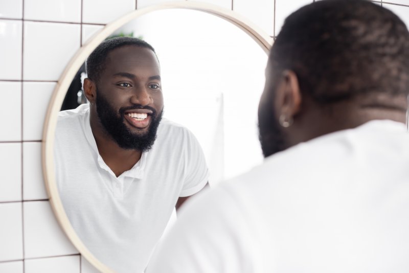 A man looking in a mirror at his dental implants